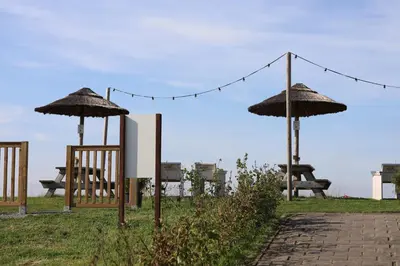 two chairs and umbrellas in a park with a table at Safari Lodges in Nieuwe Wetering