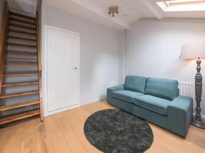 a living room with a blue couch and a rug at Hosted by wendy Old city charming accommodation in Wassenaar