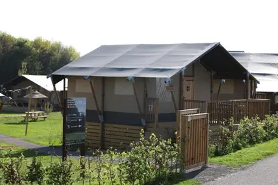 a house with a blue awning in a garden at Safari Lodges Premium in Nieuwe Wetering