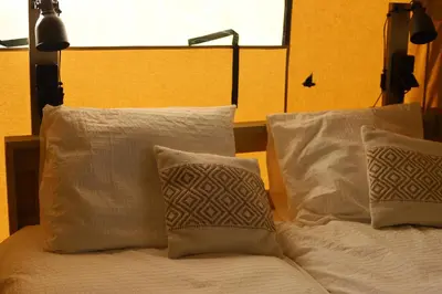 a bed with white pillows and a lamp on it at Safari Lodges Premium in Nieuwe Wetering