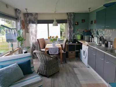 a kitchen with a table and a dining room at Tinyhouse CARPE DIEM in Dirkshorn