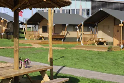 a picnic table with a umbrella and a playground at Safari Lodges XL in Nieuwe Wetering