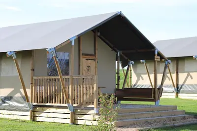 a small house with a porch and a white tent at Safari Lodges XL in Nieuwe Wetering