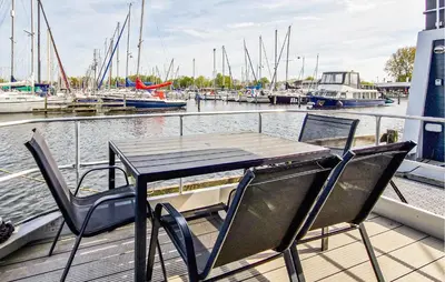 a table and chairs on a dock with boats in the water at 2 Bedroom Amazing Ship In Naarden in Naarden