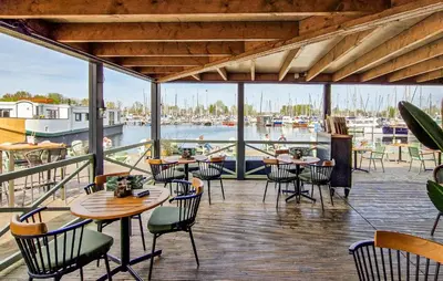 a restaurant with tables and chairs and a marina at Sydney in Naarden