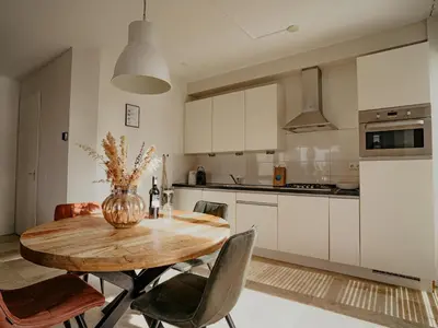 a kitchen with a wooden table with chairs and a vase at Seaside Stay in Egmond in Egmond aan Zee