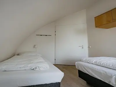 two beds in a room with white walls at Seaside Stay in Egmond in Egmond aan Zee