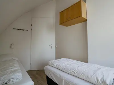 a bedroom with two beds and a wooden cabinet at Seaside Stay in Egmond in Egmond aan Zee