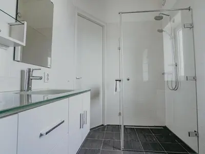 a white bathroom with a shower and a sink at Seaside Stay in Egmond in Egmond aan Zee