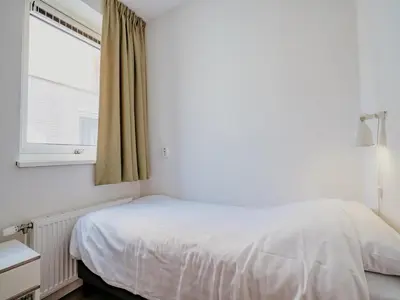 a bedroom with a white bed and a window at Spacious Lakeside Retreat in Uitgeest