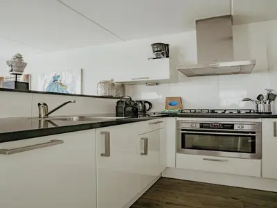 a white kitchen with a sink and a stove at Spacious Lakeside Retreat in Uitgeest