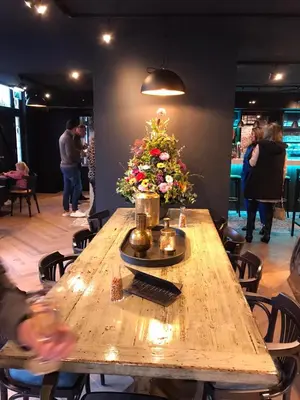 a wooden table with a flower arrangement on it at Boutique Hotel Noordeinde in Rijnsburg