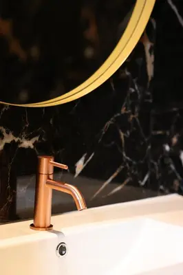 a bathroom sink with a gold faucet and a mirror at Boutique Hotel Noordeinde in Rijnsburg