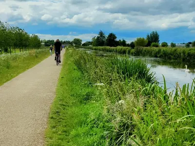a man riding a bike down a path next to a river at Park De Driesprong in Nieuwveen