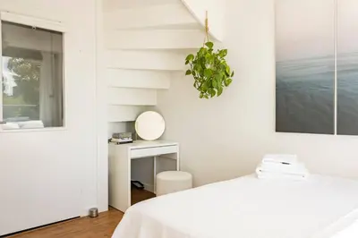 a white bedroom with a white bed and a mirror at My Apartment on the Water in Amsterdam