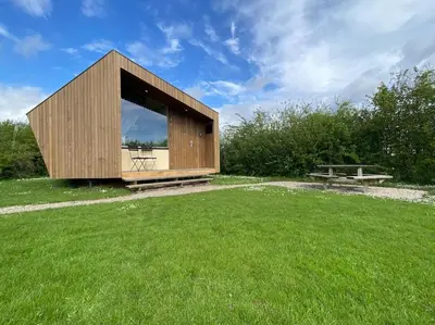 a small wooden building in a field of grass at Design huisje vrij in het groen in IJsselstein