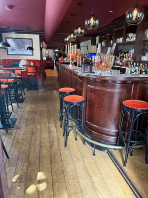 a bar with red stools in a restaurant at Tante Bed 44A in Voorschoten