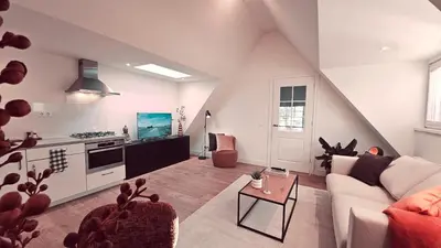 a living room with a white couch and a kitchen at Tante Bed 44A in Voorschoten
