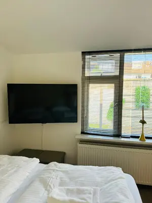 a bedroom with a bed and a flat screen tv at Studio 41 Sunshine in Noordwijk aan Zee