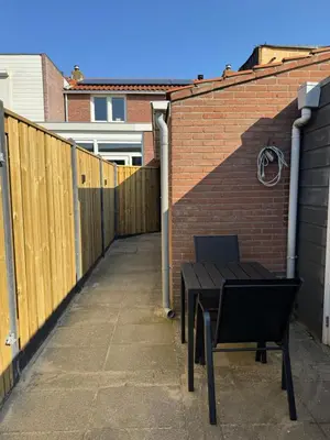 a wooden fence and a bench next to a brick wall at Studio 41 Sunshine in Noordwijk aan Zee