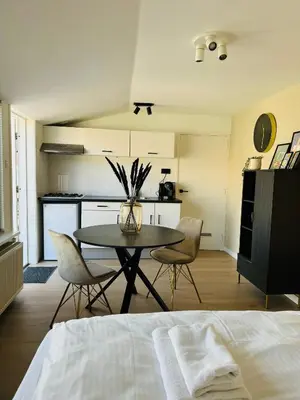 a room with a table and chairs and a kitchen at Studio 41 Sunshine in Noordwijk aan Zee