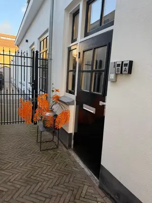 a building with a black door and chairs in front of it at Tante Bed 44 B in Voorschoten