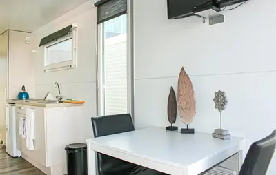 a kitchen and dining room with a white table and chairs at Havenlodge Lelystad in Lelystad