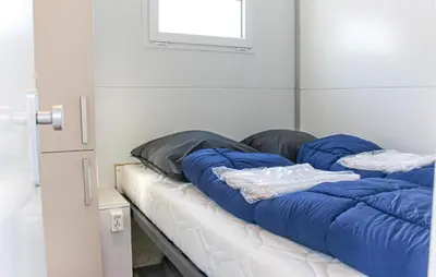 a bed with blue pillows on it in a room at Havenlodge Lelystad in Lelystad