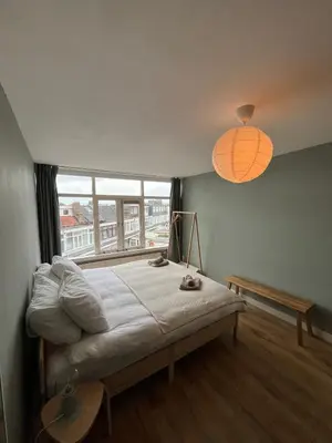 a bedroom with a bed and a large window at Haarlem jaren' 30 huis Stad & Strand in Haarlem