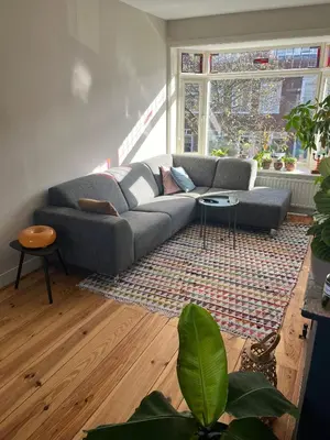 a living room with a couch and a large window at Haarlem jaren' 30 huis Stad & Strand in Haarlem