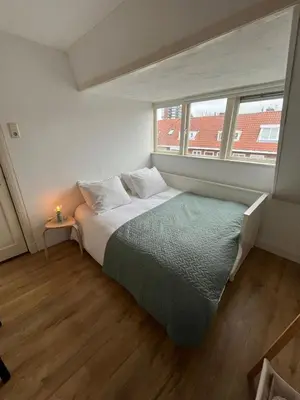 a bed in a room with a large window at Haarlem jaren' 30 huis Stad & Strand in Haarlem
