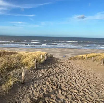 a sandy beach with a fence and the ocean at Het Klokkenest in Katwijk aan Zee