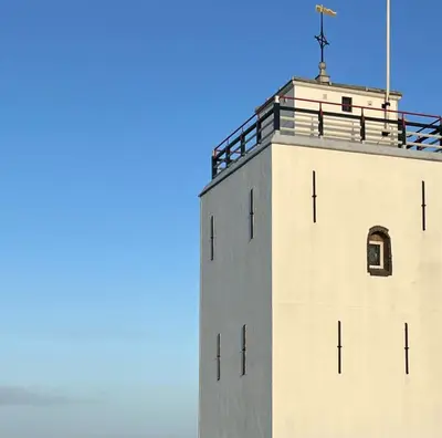 a white tower with a cross on top of it at Het Klokkenest in Katwijk aan Zee