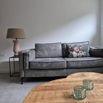 a grey couch in a living room with a table at Het Klokkenest in Katwijk aan Zee