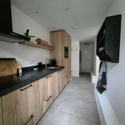 a kitchen with wooden cabinets and black counter tops at Het Klokkenest in Katwijk aan Zee