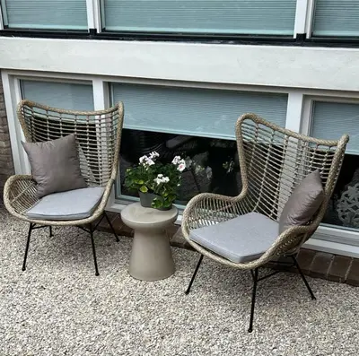 two wicker chairs and a vase of flowers on a patio at Het Klokkenest in Katwijk aan Zee