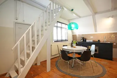 a kitchen and dining room with a staircase and a table and chairs at Dok Apartments in Amsterdam