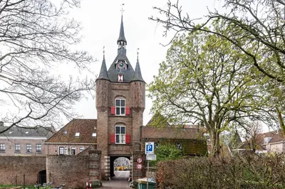 an old building with a tower with a clock on it at Huize de Lekpoort - The Stork Loft - Loft Apartment in Vianen Center in Vianen