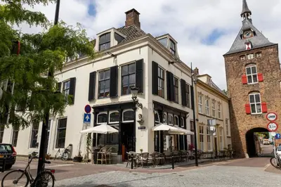 a white building with a clock tower on a street at Huize de Lekpoort - The Stork Loft - Loft Apartment in Vianen Center in Vianen