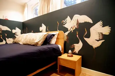 a bedroom with a bed with white birds painted on the wall at Spacious Suite at Park and Museum in Amsterdam
