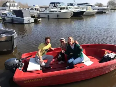 three people sitting on a red boat in the water at Dobberhuisje in IJsselstein