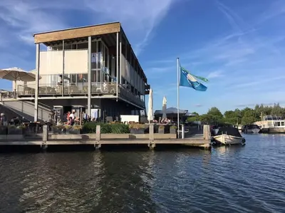 a building on a dock on the water with a flag at Dobberhuisje in IJsselstein