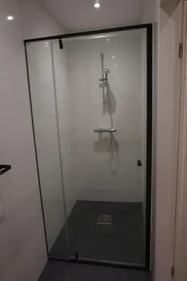 a shower with a glass door in a bathroom at Zen Beach Apartment in Noordwijk aan Zee