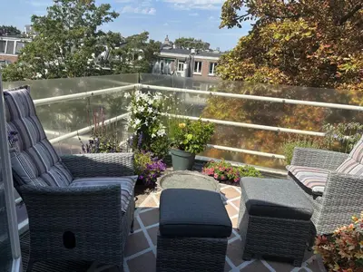 a patio with wicker chairs and tables on a balcony at The Elegant Amsterdam Apartment in Amsterdam