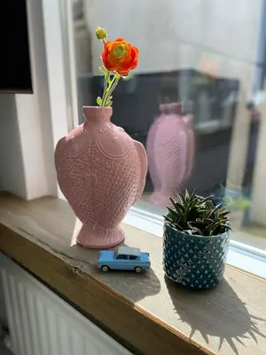 a vase with a flower and a toy car on a window sill at Lola's Beachhouse in Noordwijk aan Zee