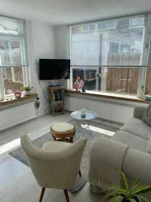 a living room with a couch and a chair and a tv at Lola's Beachhouse in Noordwijk aan Zee