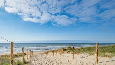 a sandy beach with a fence in front of the ocean at Lola's Beachhouse in Noordwijk aan Zee