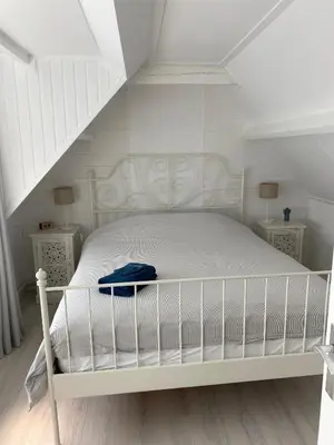 a white bed in a white room with stairs at Lola's Beachhouse in Noordwijk aan Zee