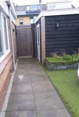 a sidewalk in front of a house with a fence at Julia's Holidayhome in Egmond-Binnen