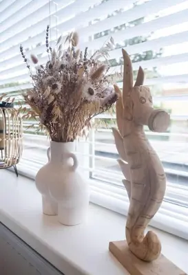 a statue and a vase with flowers on a window sill at Julia's Holidayhome in Egmond-Binnen